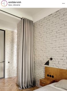 a bedroom with white brick walls and wood flooring