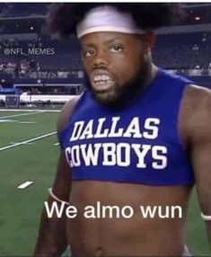 a man with no shirt on standing in front of a football field wearing a bandana