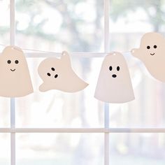 three ghost decorations hanging on a line in front of a window