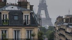 the eiffel tower is seen in the distance from buildings on a rainy day