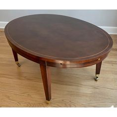 an oval table with wheels on the legs and a wooden top, sitting on a hard wood floor