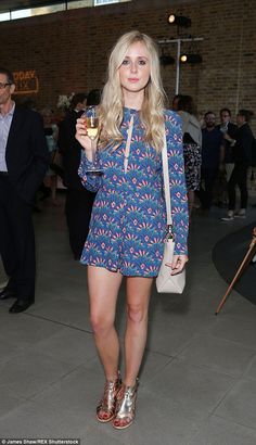 a woman holding a glass of wine in her right hand and standing on the floor