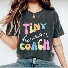 a woman wearing a tiny human coach t - shirt with her hands in her pockets