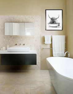 a bath room with a tub a sink and a painting on the wall above it