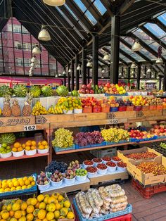 an outdoor market with lots of fresh fruits and vegetables on display in baskets, along with hanging lights