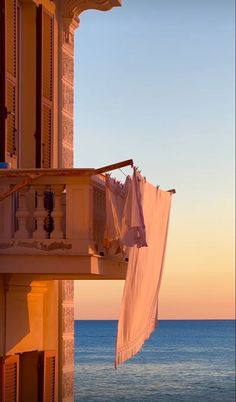 clothes hanging out to dry in front of an apartment building overlooking the ocean at sunset