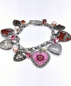 A lovely heart charm bracelet with silver charms. Some charms have been colorized with resin and paint. There are also Czech glass flower charms. The bracelet fits. a 7 inch wrist. Heart-shaped Charms Beaded Bracelets For Jewelry Making, Valentine's Day Metal Charm Bracelet With Heart Beads, Pink Heart-shaped Beaded Bracelets With Charms, Handmade Silver Charm Bracelet For Valentine's Day, Pink Heart Charm Bracelet In Sterling Silver, Handmade Metal Heart Charm Bracelet, Pink Sterling Silver Charm Bracelet With Heart, Pink Heart-shaped Sterling Silver Charm Bracelet, Sterling Silver Pink Heart Charm Bracelet