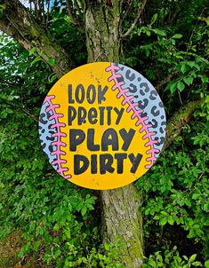 a sign that says look pretty play dirty on a tree