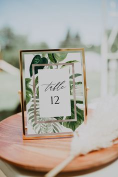 the table numbers were placed on top of each other and surrounded by greenery, such as palm leaves