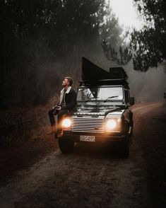 a woman sitting on the hood of a vehicle