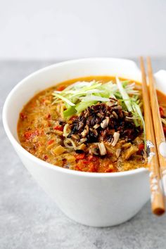 a white bowl filled with soup next to chopsticks