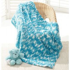 a blue and white blanket sitting on top of a chair next to a teddy bear