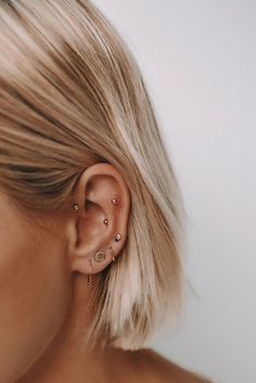 a woman with blonde hair is wearing an ear cuff and has two piercings on her ears