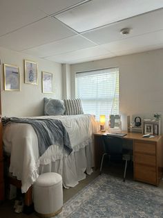 a bedroom with a bed, desk and chair next to a window in the corner