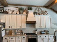 a kitchen with white cabinets and an oven in the center is decorated with greenery