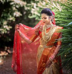 a woman in an orange and gold sari holding a red shawl over her shoulder