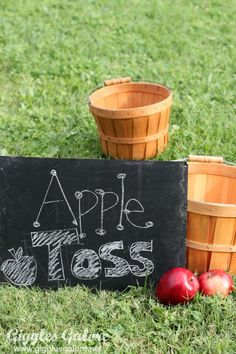 an apple sits next to two wooden buckets on the grass with apples in them