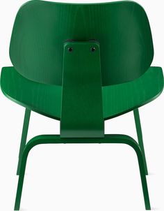 a green chair sitting on top of a white floor next to a wooden frame and metal legs