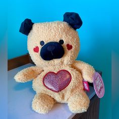 a brown teddy bear with a heart on it's chest sitting on a table