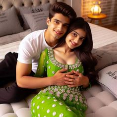 a young man and woman sitting on top of a bed next to each other smiling