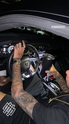 a man with tattoos on his arm driving a car