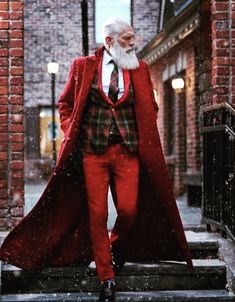 a man in a red suit and white beard is walking down the street with his coat over his shoulders