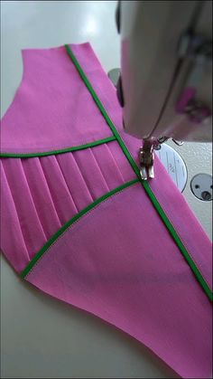 a pink piece of cloth being sewn on with a sewing machine in the background