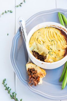 a bowl of shepherd's pie and green beans on a plate