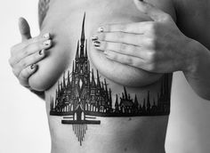 a black and white photo of a woman's stomach with a castle tattoo on it