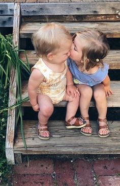 two small children sitting on steps kissing each other