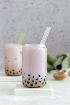 two glasses filled with liquid sitting on top of a white table next to each other