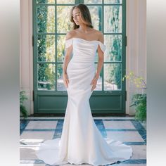 a woman in a white wedding dress posing for the camera with her hands on her hips