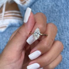 a woman's hand with white manies holding a ring and a diamond on it