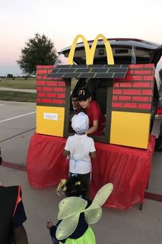 two children standing in front of a mcdonald's car with an adult and child