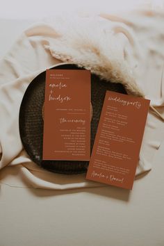 the wedding stationery is laid out on top of a plate with two folded menus