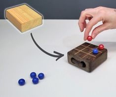 a person is playing with wooden blocks and balls on a white counter top, while another hand reaches for them