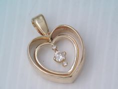 a heart shaped pendant with two diamonds on it's sides, sitting on a white surface