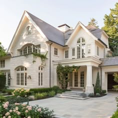 a large white house with lots of windows and bushes around it's front entrance