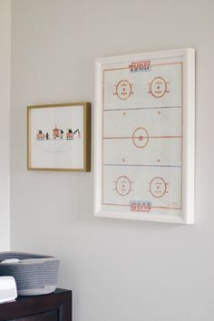 a hockey rink is hung on the wall above a dresser in a bedroom with two framed pictures