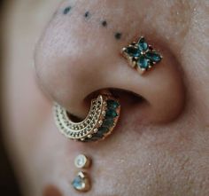 a close up of a person's ear with piercings on it and two different colored stones