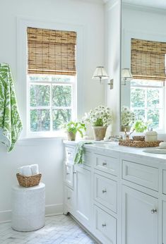 a bathroom with white cabinets and green towels on the window sill above the sink