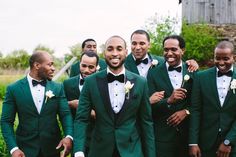 a group of men in green suits and bow ties standing next to each other smiling