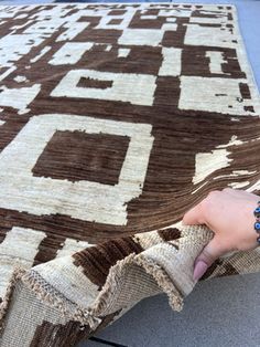 a person is holding onto a brown and white rug