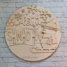 a wooden sign that says let it snow on the side of a brick wall with a sleigh