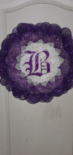 a purple and white wreath with the letter ub on it's front door