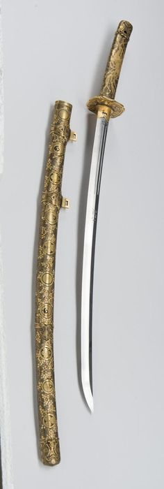 two gold colored swords are next to each other on a white surface, one has a long blade and the other has a pointed tip