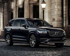 a black volvo suv parked in front of an old building at night with lights on