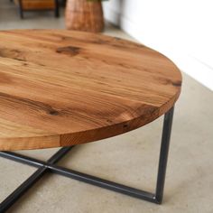 a wooden table sitting on top of a cement floor next to a vase with flowers