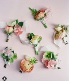 several different types of flowers are arranged on a pink surface with white ribbons and green leaves