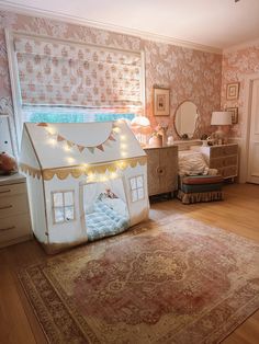 a dollhouse bed in the middle of a room with a rug on the floor